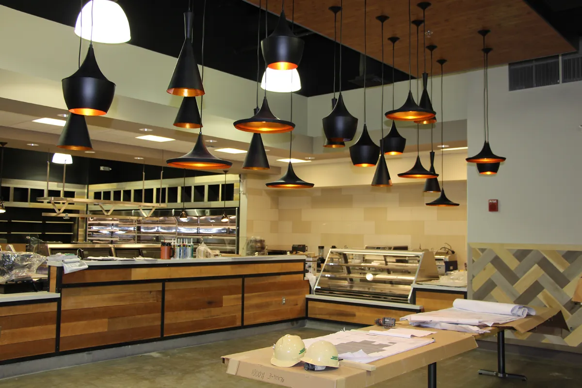 Upscale restaurant or bar with wood tables, pendant lights, and shelved display wall