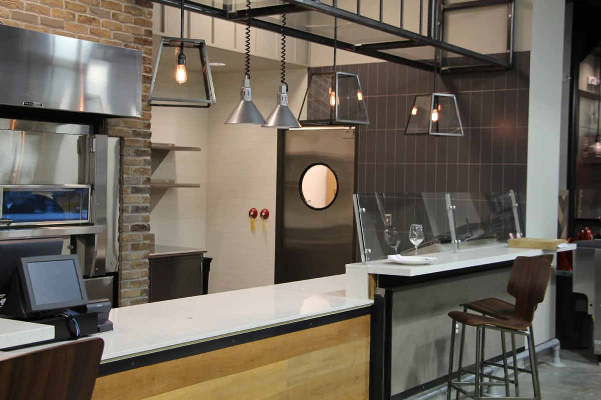 Modern restaurant or café interior with open kitchen and pendant lighting