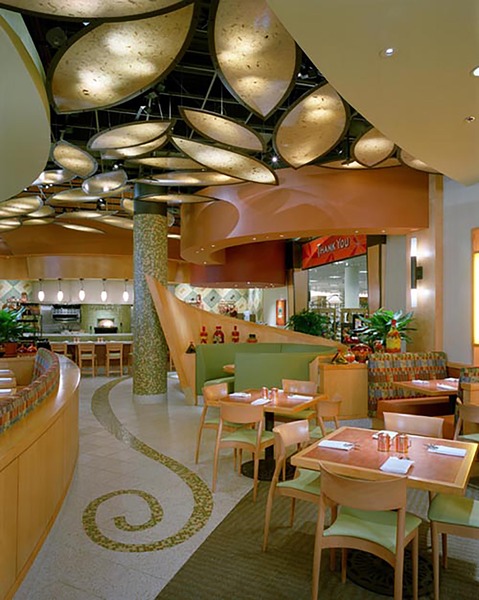 A warmly lit dining area at Nordstrom with curved wood ceiling details, decorative lighting, and lounge seating