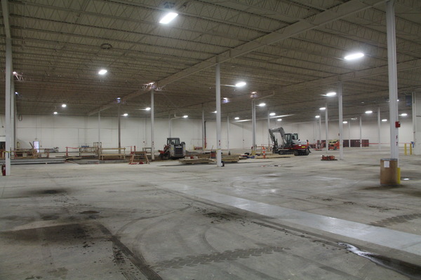 Empty warehouse or large commercial space with concrete floors and overhead lighting