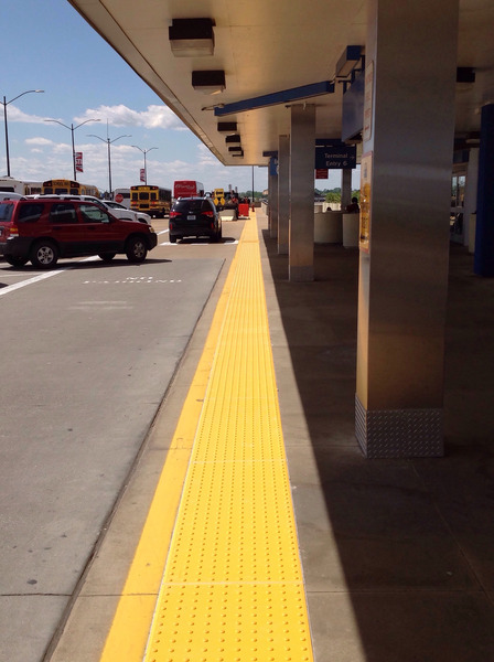 Yellow tactile paving strips installed at a transit or pedestrian walkway