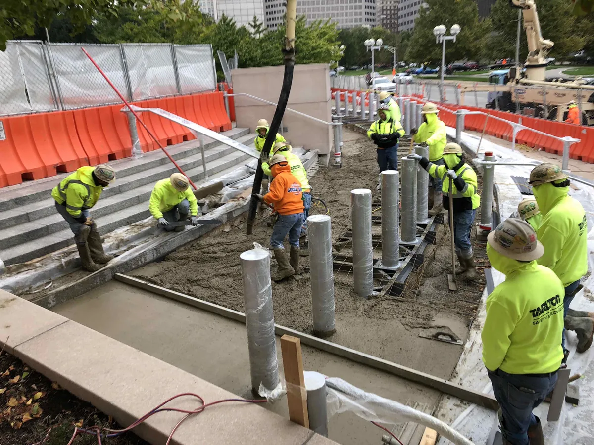 Construction working pouring concrete sidewalk and stairs