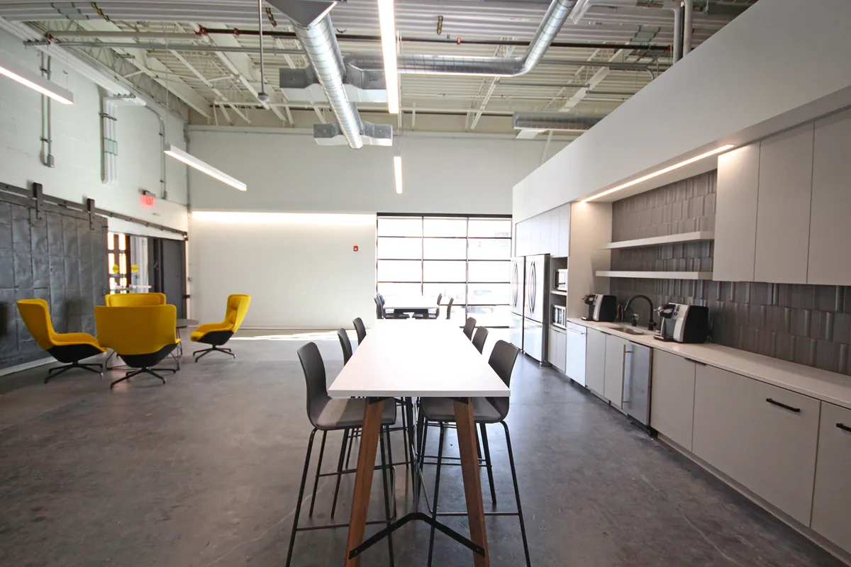 Open meeting or dining area with long white table and yellow accent chairs
