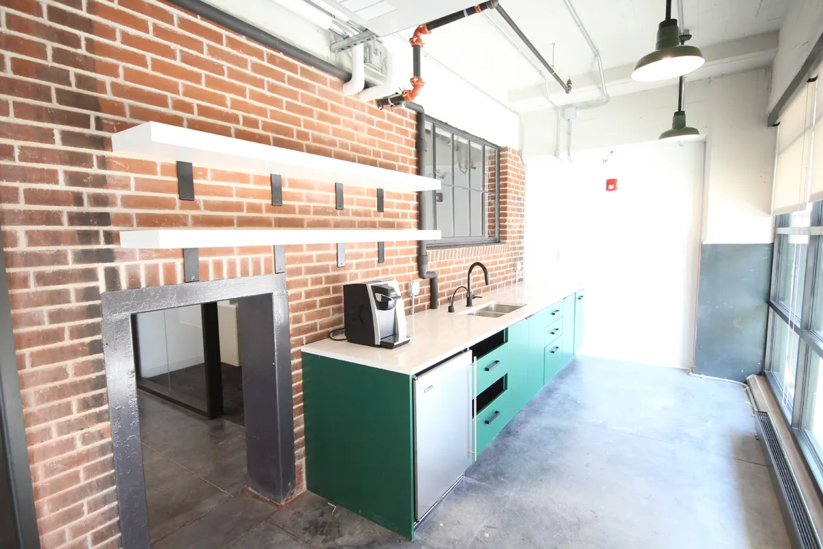 Contemporary kitchen or café area with green island, brick wall, and pendant lighting