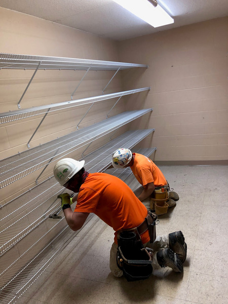 Construction worker in safety gear installing metal storage shelving