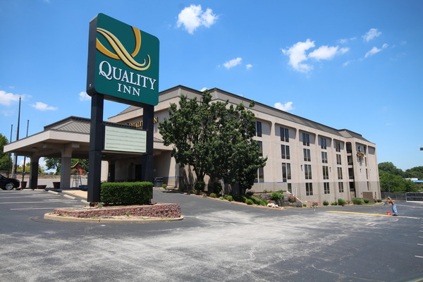 Exterior of a Quality Inn hotel with palm trees and blue sky