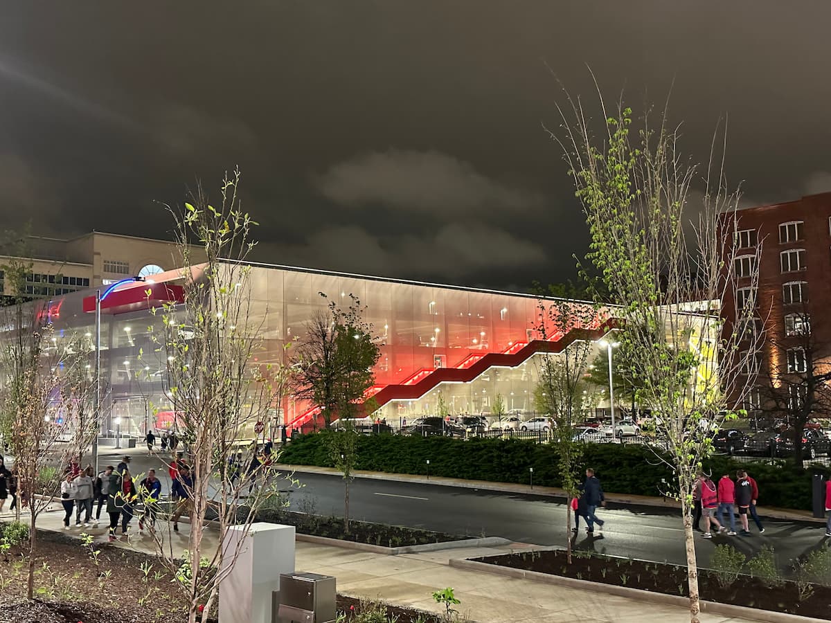 Outdoor plaza or courtyard with a red angular shade structure and mural wall