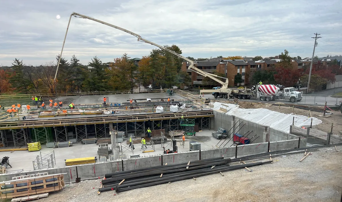 Pouring concrete at construction site with large crane