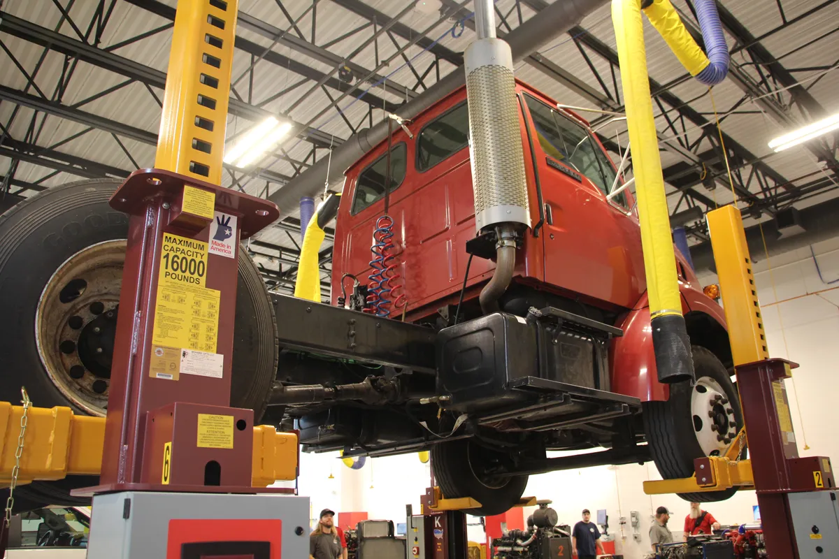 Large yellow crane lifting truck