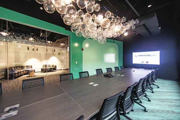 Modern conference room with green accent wall, pendant lighting, and long table