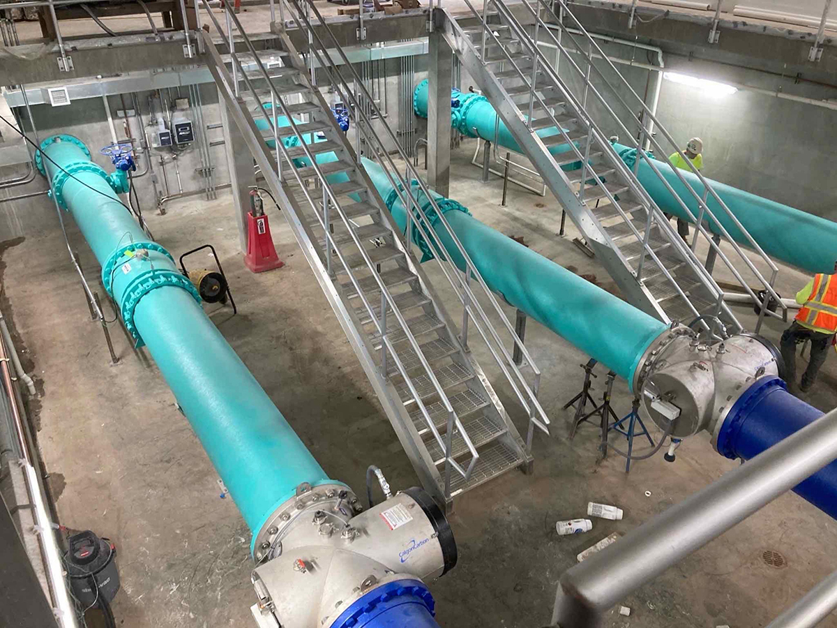 Teal utility pipes being installed at an underground construction site