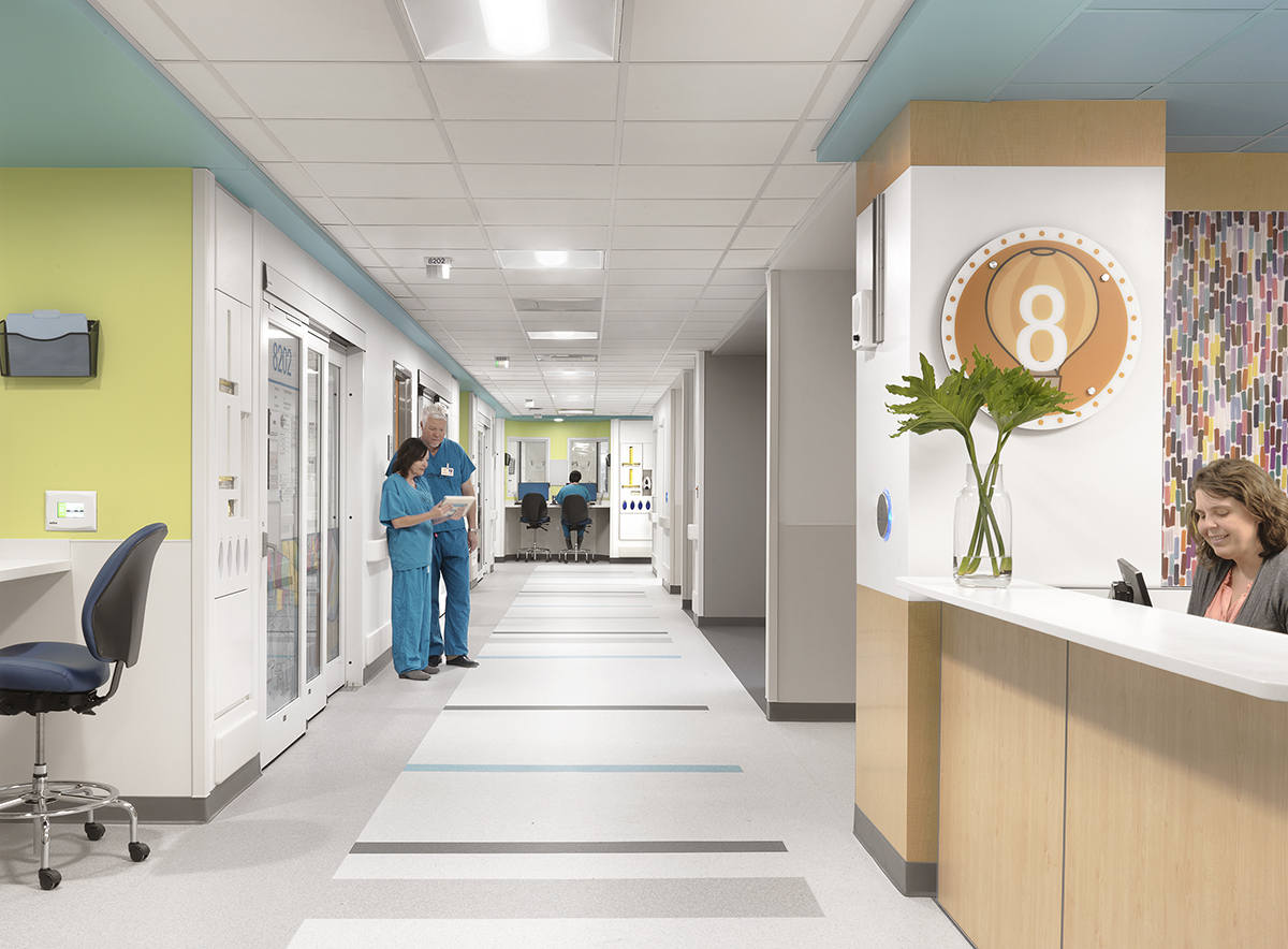 Healthcare facility corridor with medical equipment and staff in scrubs