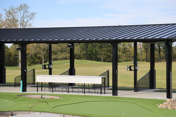 Exterior of a newly completed tee-boxes with dark metal roof and putting green
