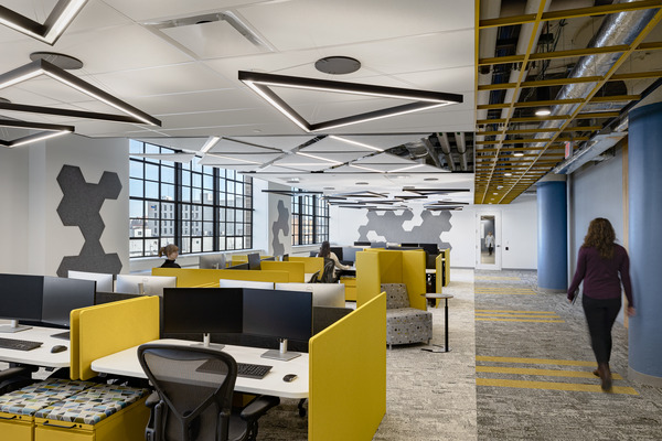 Modern open office with yellow accents, workstations, and large windows