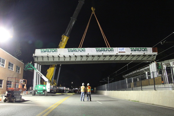 Covered pedestrian bridge or walkway at night craned into place